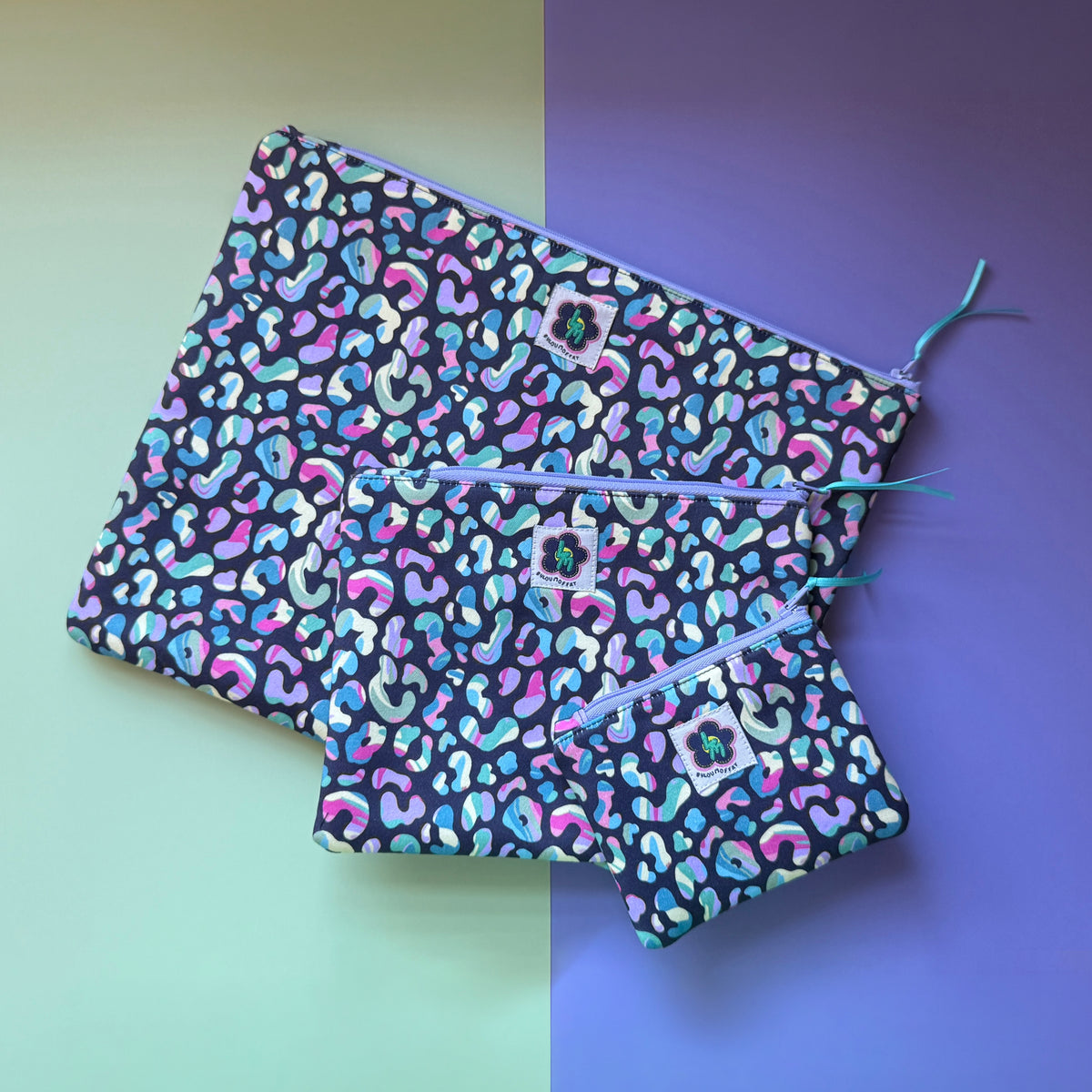 Three leopard-print zip pouches in small, medium and large, with multicoloured spots on a dark background.