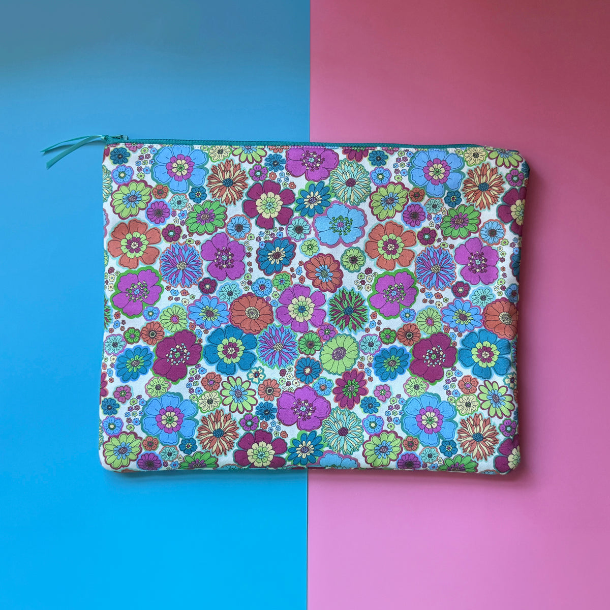 Back of the large zip pouch, showing colourful retro flowers on an off white background and a teal zip.