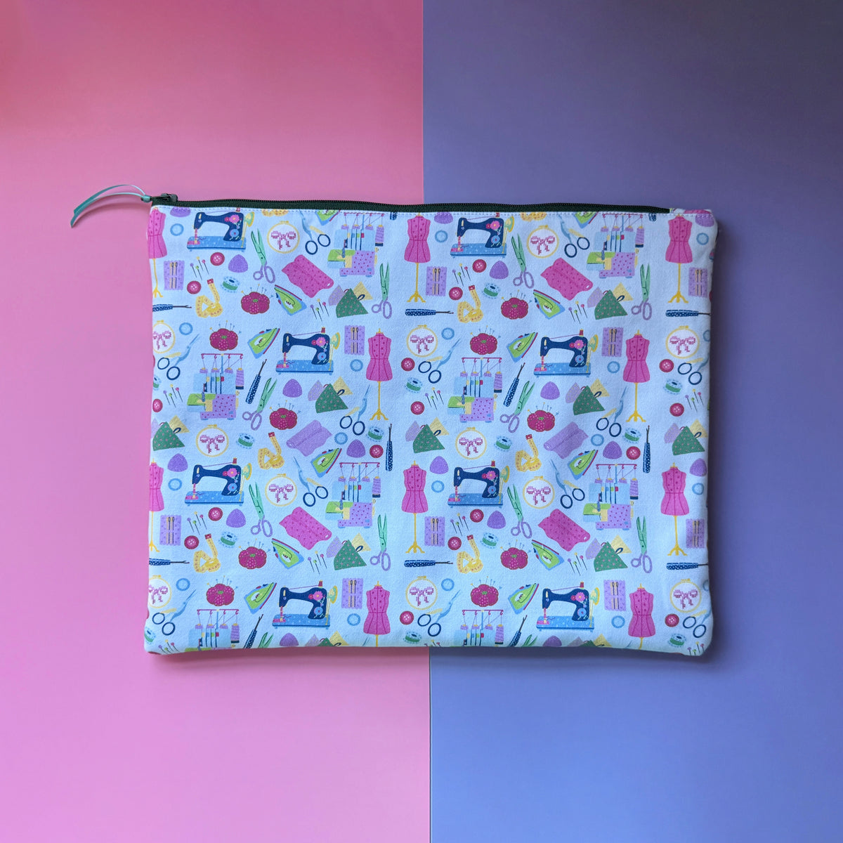 Back of the large pale blue sewing pouch, showing colourful sewing machines, dressmaking mannequins and sewing tools.