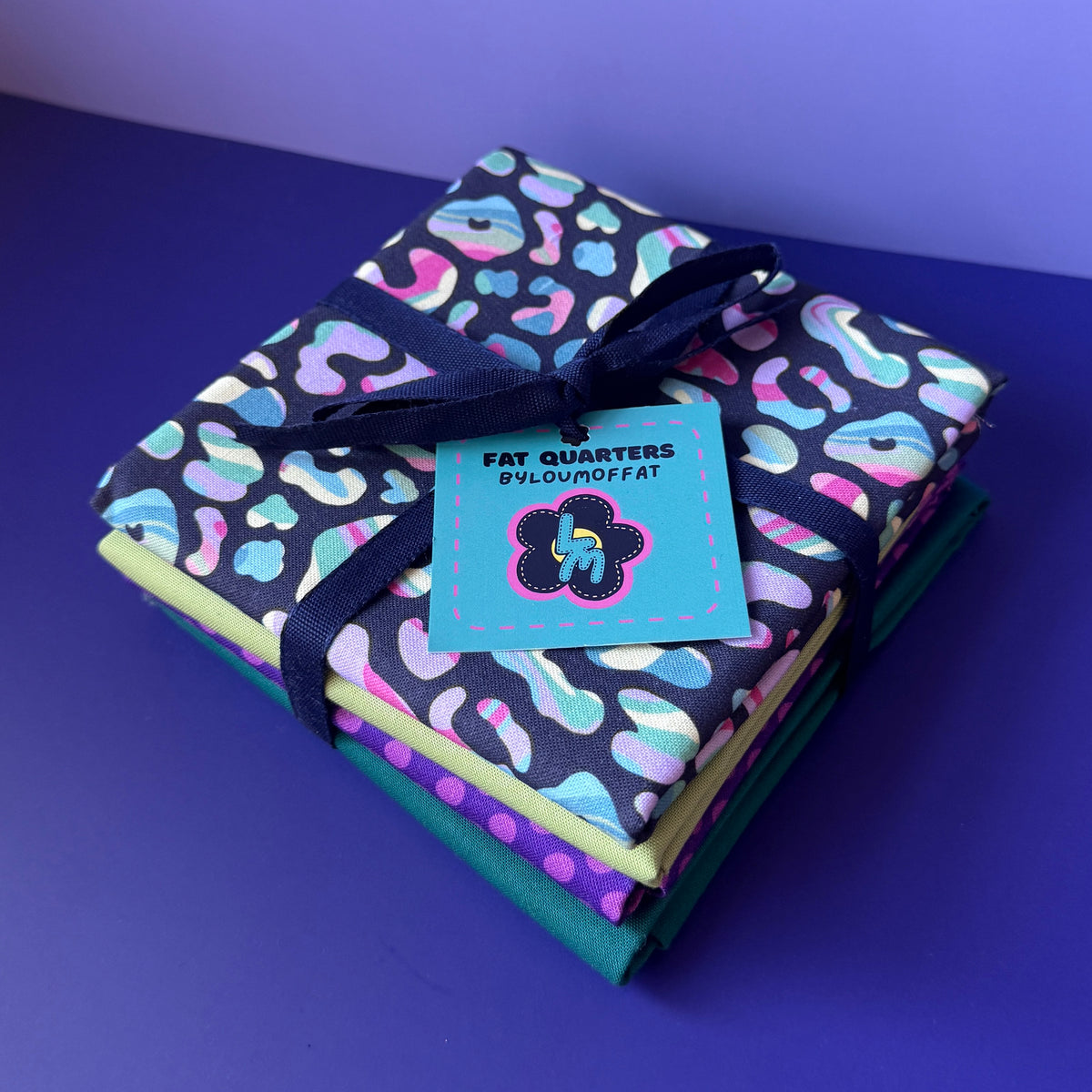 Leopard fat quarter bundle stacked and tied with navy ribbon, finished with a turquoise ByLouMoffat tag.