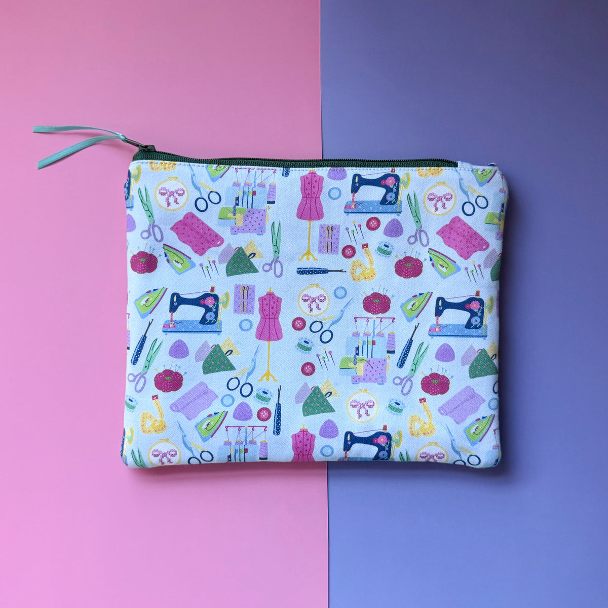 Back of the medium pale blue sewing pouch, showing a repeating pattern of sewing machines, mannequins and scissors.