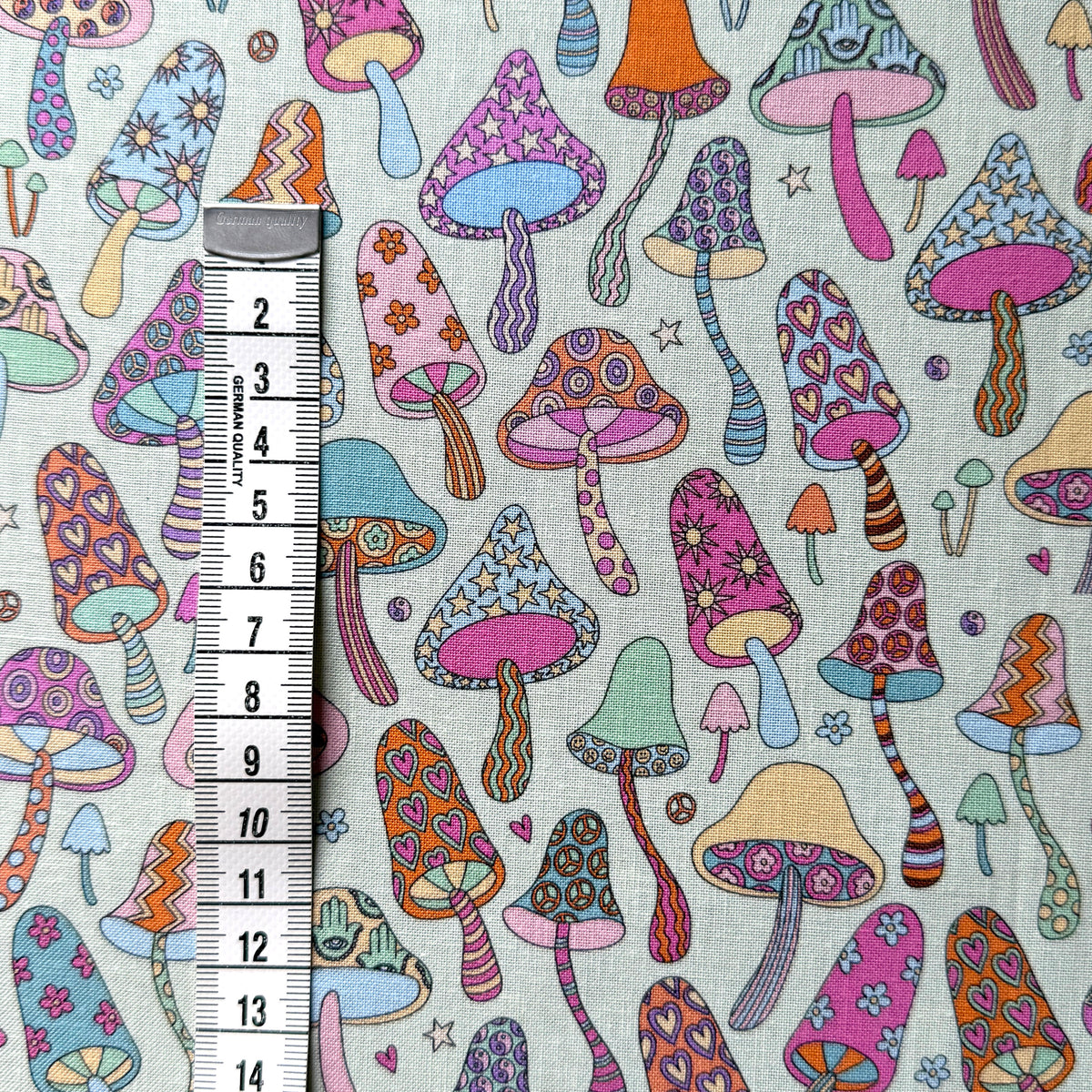 Colourful patterned mushroom fabric beside a centimetre tape measure to show the scale of the design.