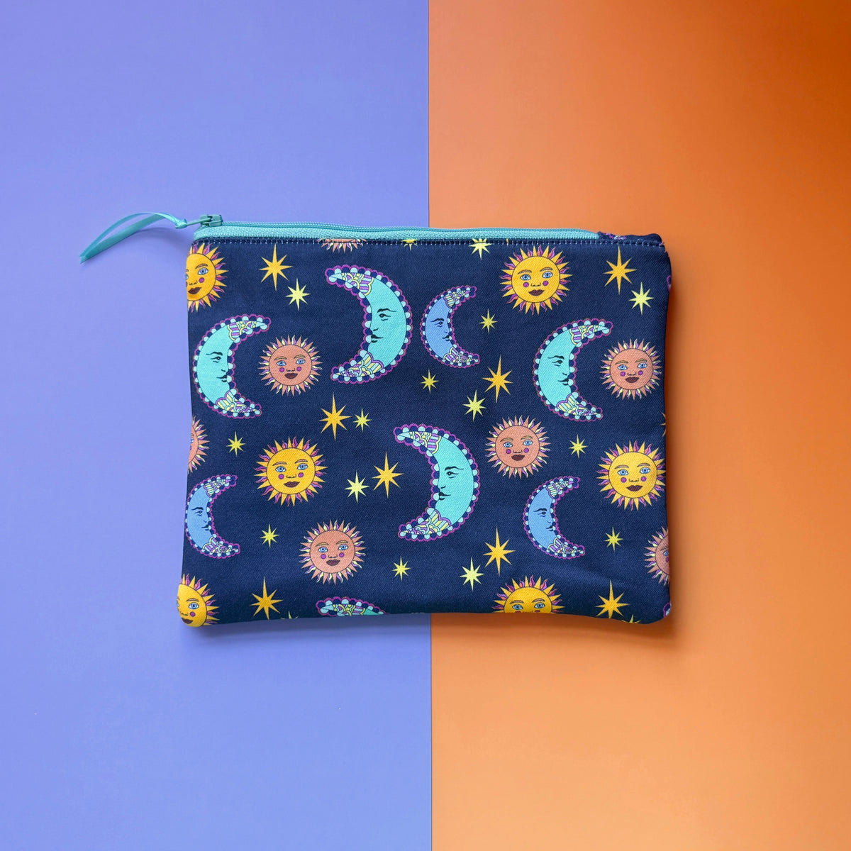 Back of the medium navy pouch, showing turquoise crescent moons, yellow and peach suns, and stars.