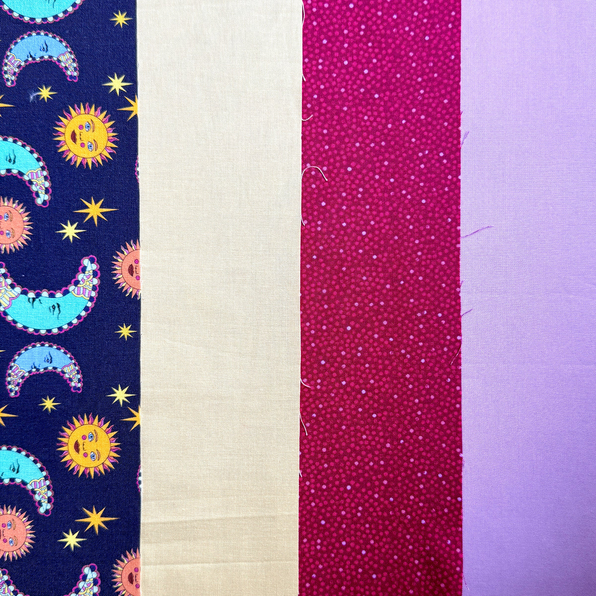 Close-up of the Sun and Moon fat quarter bundle, showing colourful celestial motifs and coordinating lilac, berry pink and yellow fabrics.