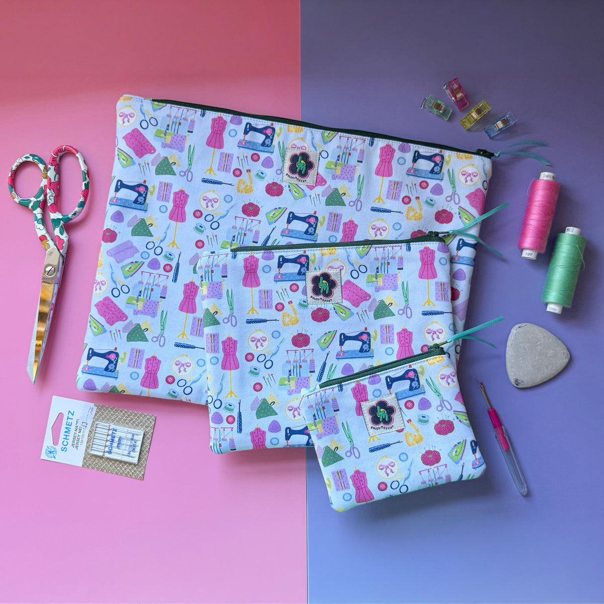Three matching sewing-print pouches in small, medium and large. Fabric features colourful sewing machines, scissors, dressmaking mannequins, embroidery hoops, unpickers and other sewing notions on a pale blue background. 