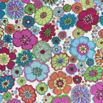 60s-inspired floral fabric laid flat, featuring pink, orange, blue, teal and lime green retro flowers on a light off white background.