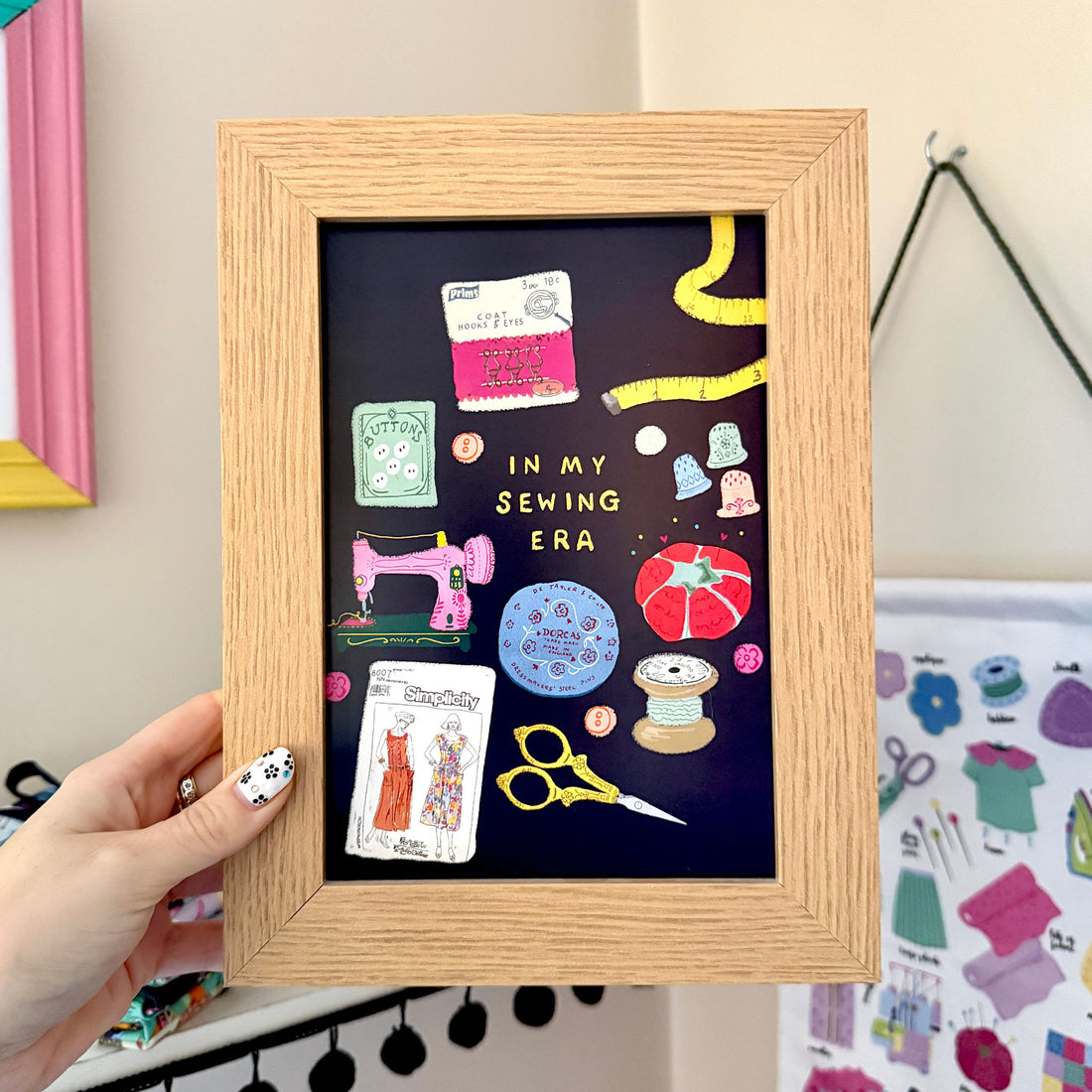 Navy In My Sewing Era print in a wooden frame, featuring colourful vintage sewing tools and accessories.