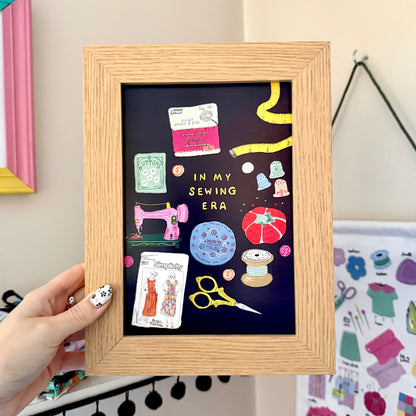 Navy In My Sewing Era print in a wooden frame, featuring colourful vintage sewing tools and accessories.