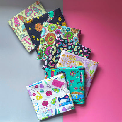 Seven folded fat quarters fanned out, featuring mushrooms, suns and moons, retro flowers, colourful leopard print, vintage flowers, hippie motifs and sewing tools.