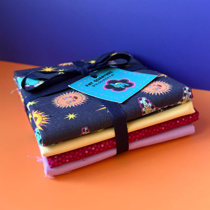 Sun and Moon fat quarter bundle stacked and tied with navy ribbon, finished with a turquoise ByLouMoffat tag.