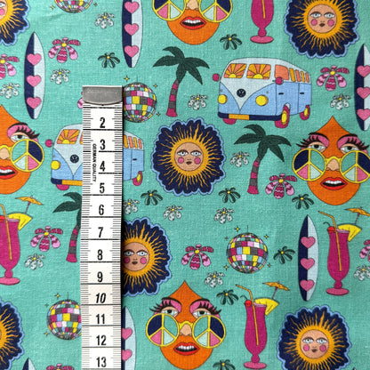 Mint green hippie fabric beside a centimetre tape measure to show the scale of the campervan, sunshine and peace-sign motifs.