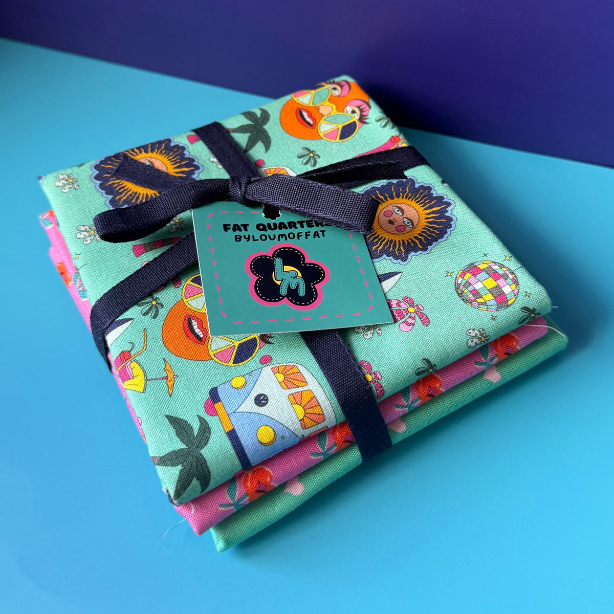 Hippie fat quarter bundle tied with a navy ribbon and turquoise ByLouMoffat tag, with the retro campervan print on top.
