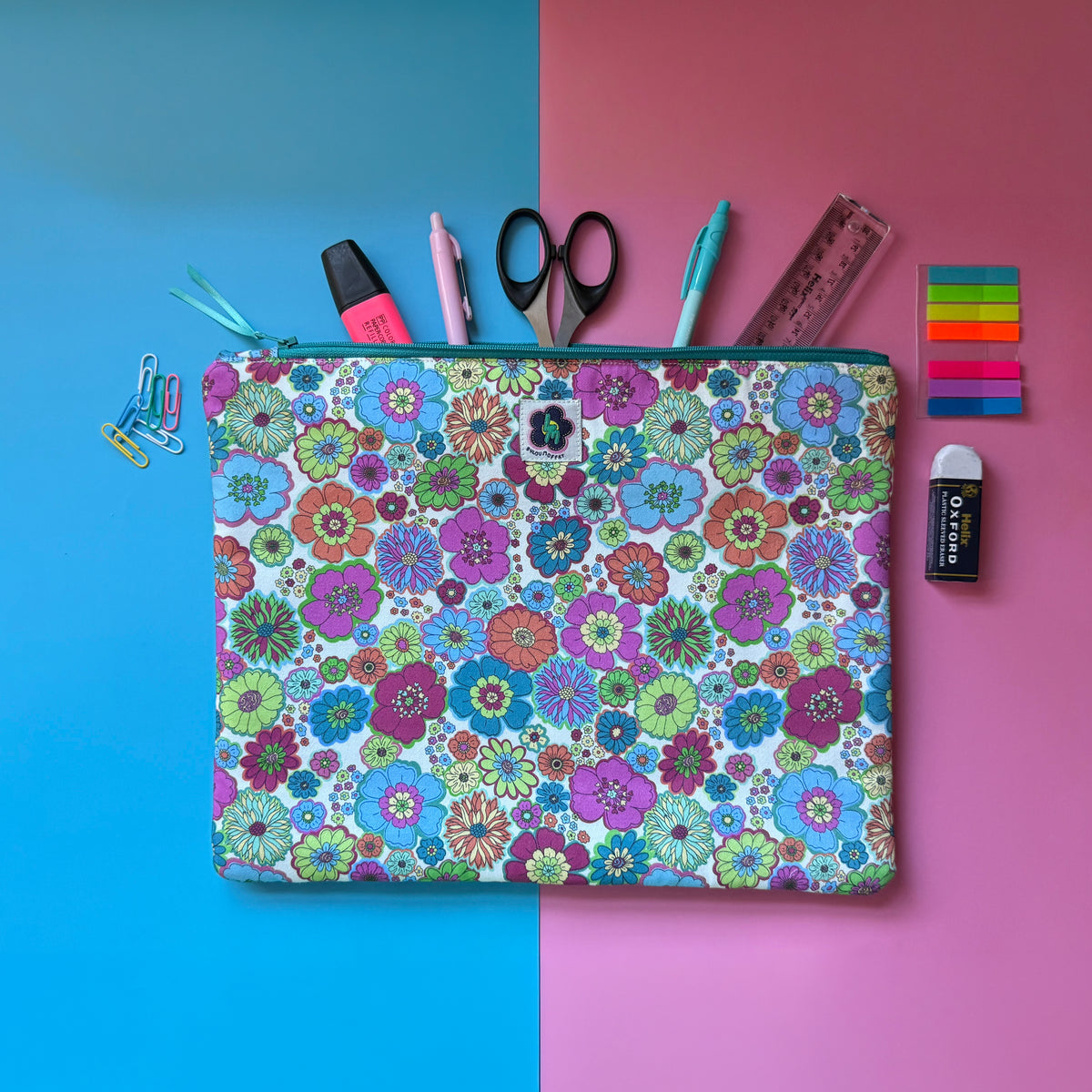 Large 60s floral zip pouch featuring colourful fabric with retro inspired florals. Shown with pens, scissors, a ruler and other stationery.