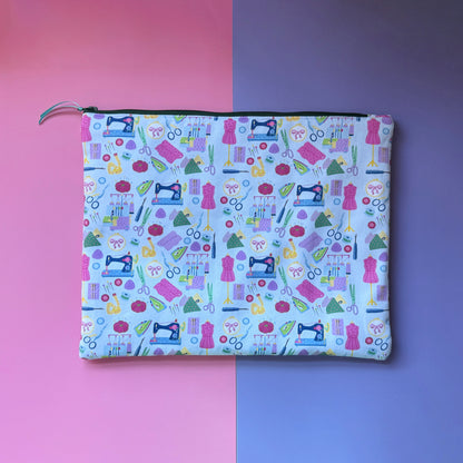 Back of the large pale blue sewing pouch, showing colourful sewing machines, dressmaking mannequins and sewing tools.
