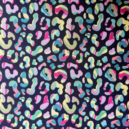 Leopard print fabric laid flat, showing multicoloured spots with striped and swirled details on a dark navy background.