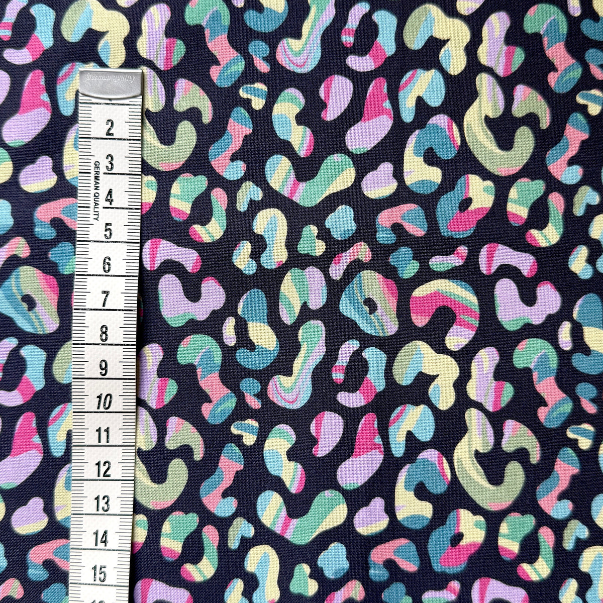 Colourful leopard print fabric beside a centimetre tape measure to show the scale of the pattern.
