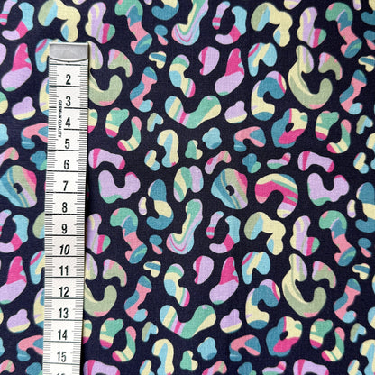 Colourful leopard print fabric beside a centimetre tape measure to show the scale of the pattern.
