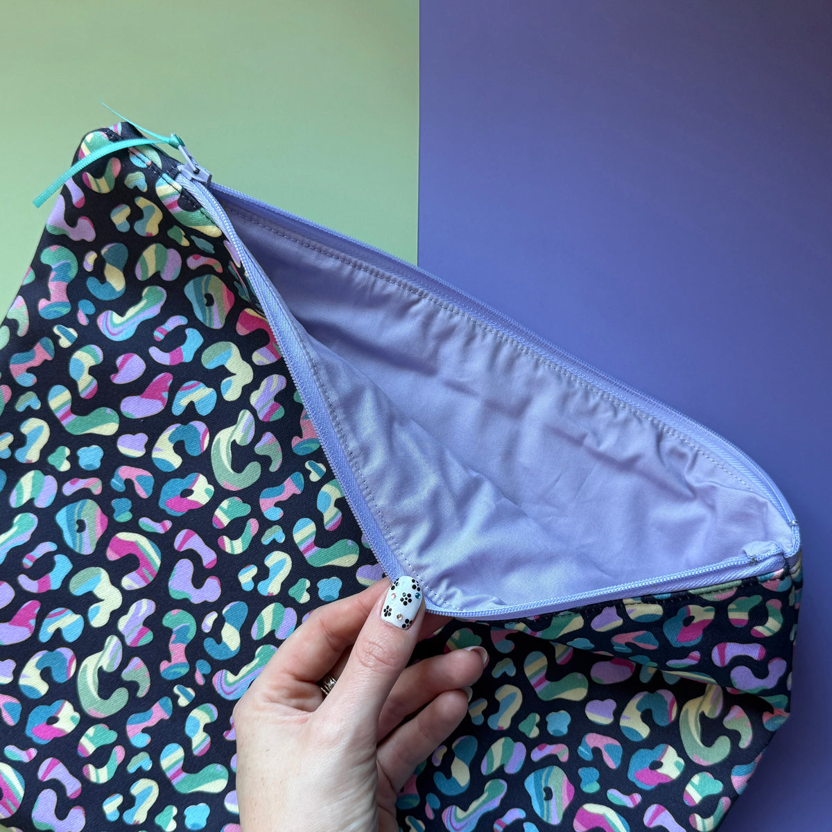 Leopard print pouch held open to reveal its plain lilac lining and matching zip.