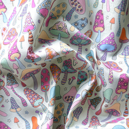 Draped mushroom print fabric showing its texture and playful pink, lilac, turquoise, orange and yellow mushroom designs.