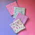 Four folded fat quarters overlapping diagonally, with colourful mushroom fabric in front of lilac, sage green gardening and pink floral paisley fabrics.