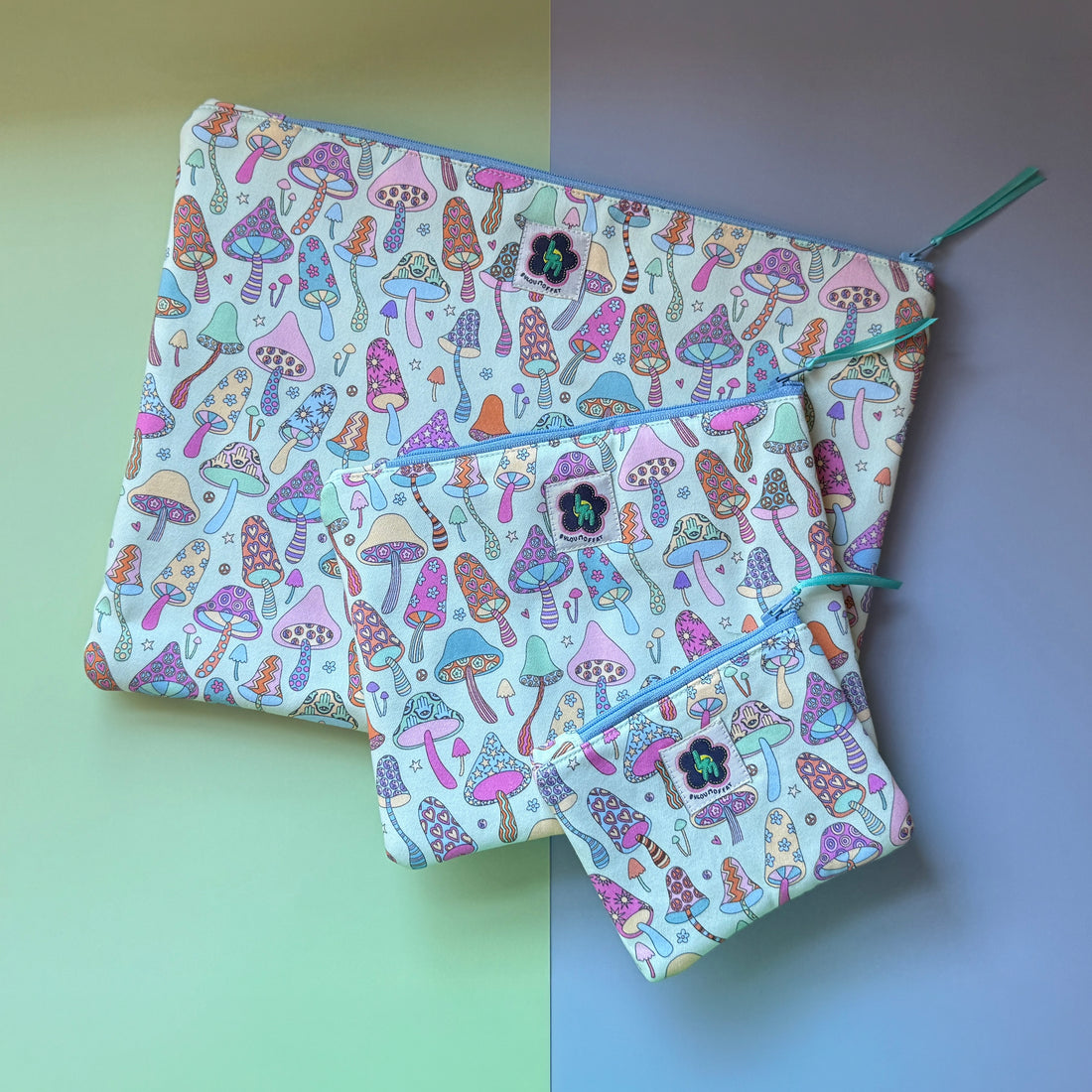 Three mushroom print zip pouches in small, medium and large, with colourful patterned mushrooms featuring stars, hearts, flowers hamsa hands and ByLouMoffat labels.