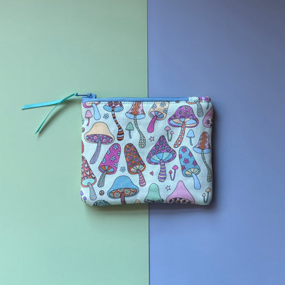 Back of the small zip pouch, showing colourful patterned mushrooms, a pale blue zip and teal ribbon pull.