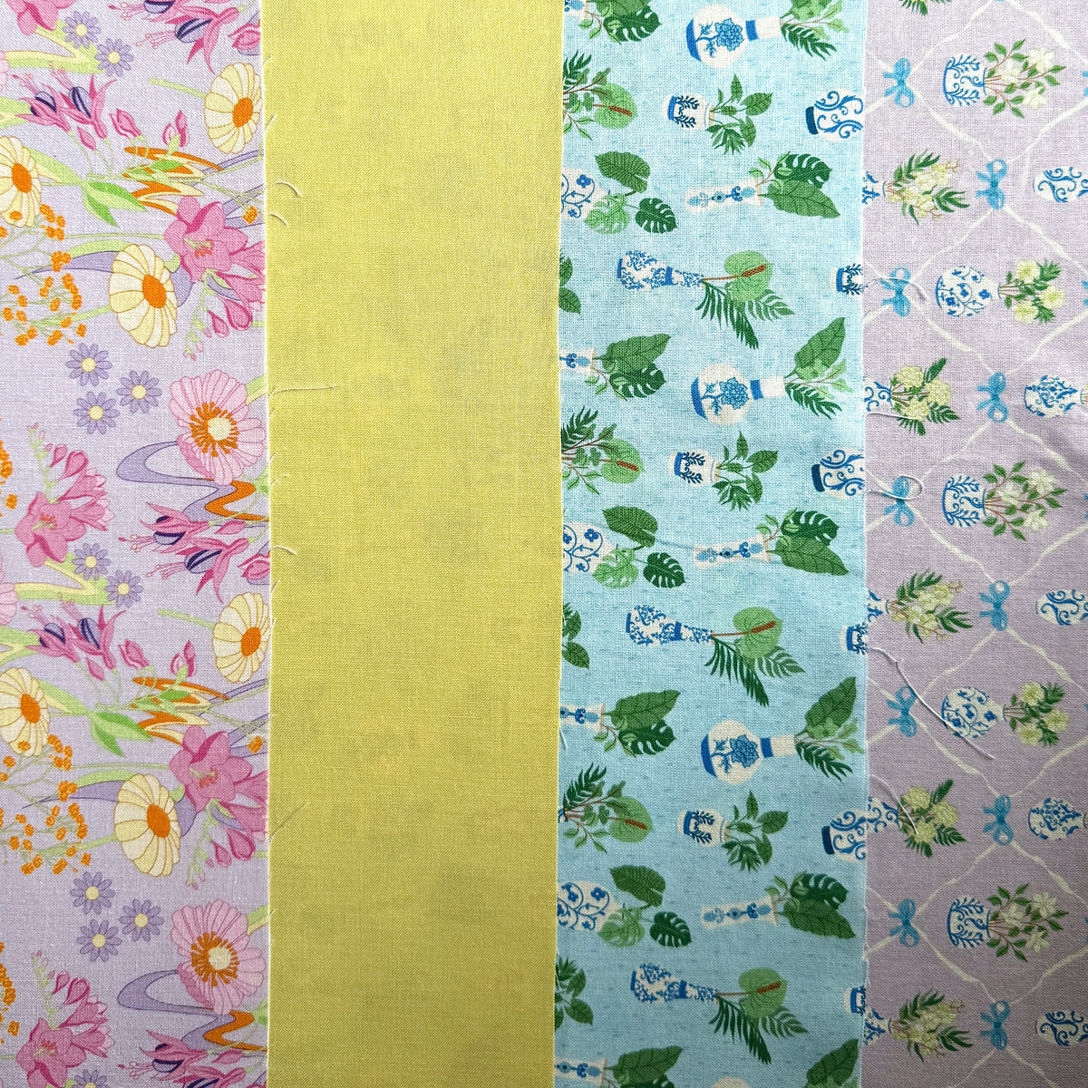 Four fabrics laid side by side, showing pink and yellow retro vintage inspired flowers, plain yellow and two coordinating potted plant prints.