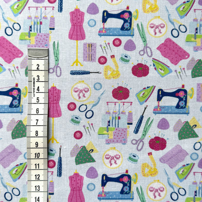 Sewing-themed fabric beside a centimetre tape measure to show the scale of the sewing machines, scissors and dress forms.
