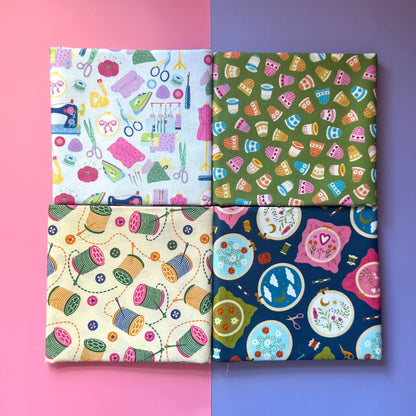 Four folded sewing-themed fat quarters arranged in a square on a pink and purple background.