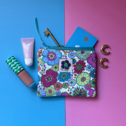 Small 60s floral zip pouch with a ByLouMoffat label, shown with cosmetics, a key, card and earrings.