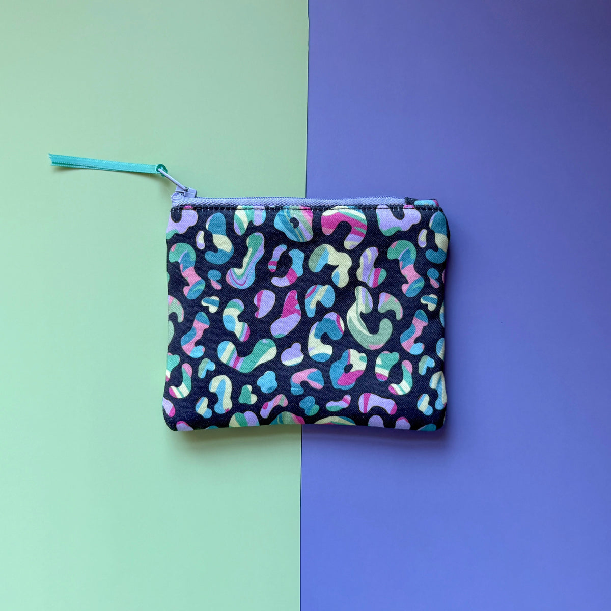 Back of the small pouch, showing colourful leopard spots, a lilac zip and teal ribbon pull. 