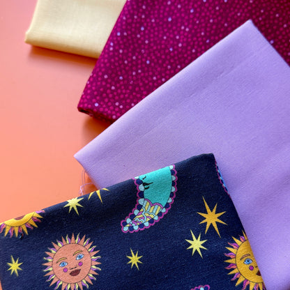 Four folded fat quarters arranged in a square, featuring a navy celestial print, pale yellow, lilac and berry pink fabrics.