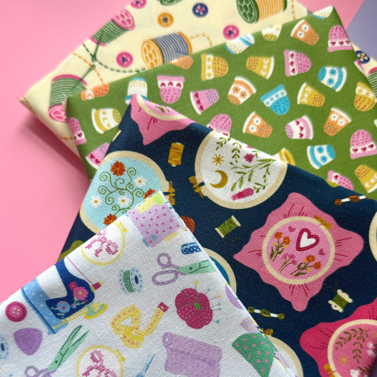 Close-up of the sewing fat quarter bundle, showing the fabric texture and colourful sewing, thimble, embroidery hoop and thread spool prints.